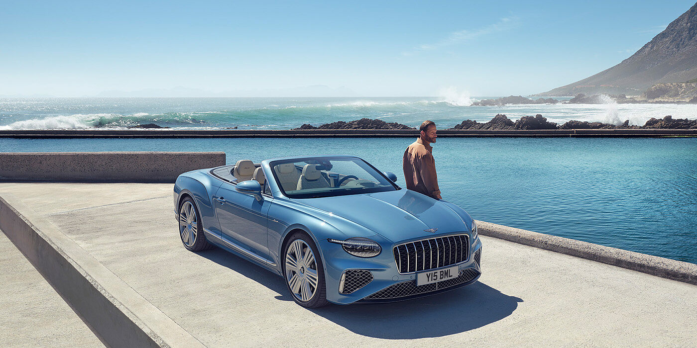 Bentley Tel Aviv New Bentley Continental GTC Azure convertible front view in Light Windsor blue paint with 22 inch ten spoke wheels parked by the sea in the sunshine