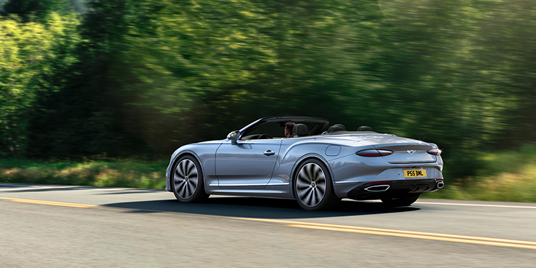 Bentley Tel Aviv New Bentley Continental GTC convertible side view in Silverlake paint with 22 inch ten spoke wheels driving dynamically on a country road